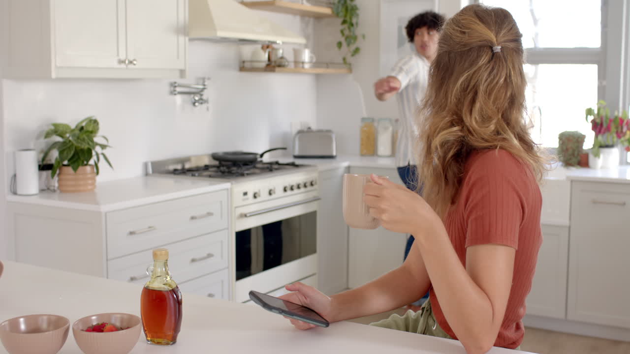 Woman preparing breakfast in modern kitchen with bowls and syrup on counter, at home