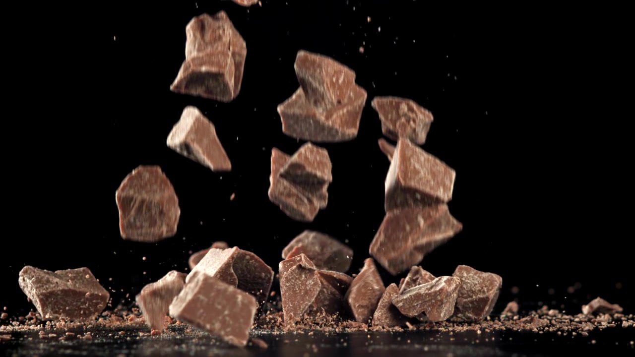 Pezzi di cioccolato che cadono al rallentatore su sfondo nero