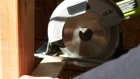 a power tool circular saw cutting a wood lumber board on a construction site