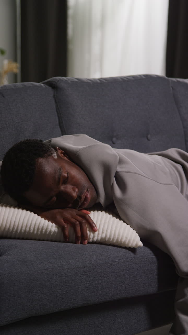 video vertical de un joven infeliz y deprimido acostado en el sofá en casa mirando ansioso y preocupado 1