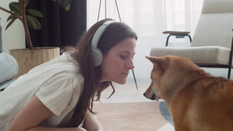 Pretty-girl-feeds-and-pets-her-dog-while-working-on-her-laptop-at-home.-Shiba-Inu.