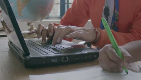 Slowmotion-shot-of-an-individual-typing-on-the-computer-and-the-other-person-writing