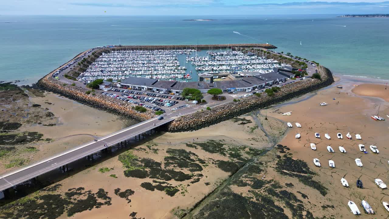 Pornichet Marina at low tide, sailboats, bridge, and boats on sandy beach, France. Aerial forward