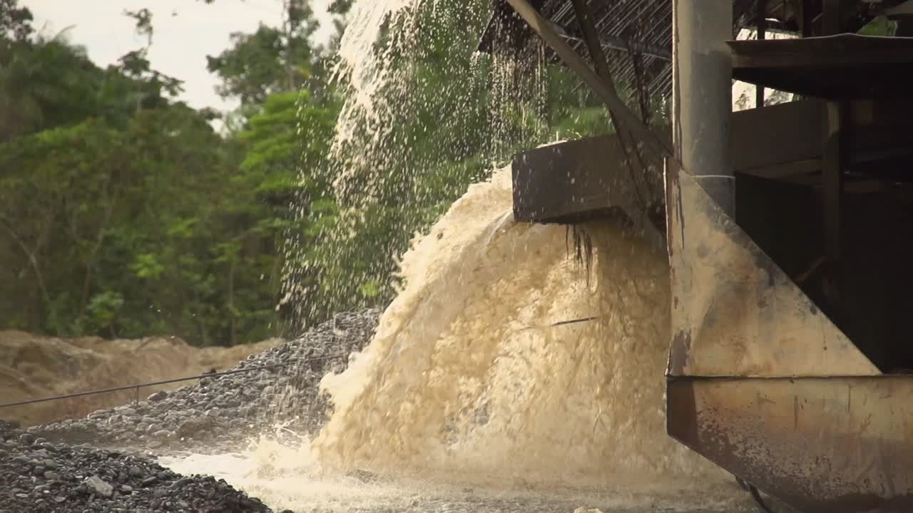 Processed sand and mud spewing out of a gold dredger in to the river in Checo, Colombia