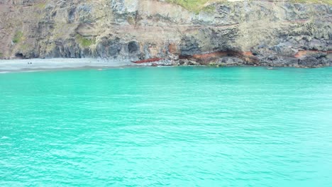 Lateral-aerial-above-beautiful-turquoise-colored-South-Pacific-Ocean-showing-diverse-volcanic-rock-formations-at-Banks-Peninsula