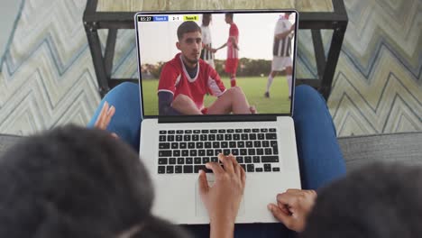 Video-De-Una-Pareja-Afroamericana-Sentada-En-Un-Sofá-Y-Viendo-Fútbol-En-Una-Computadora-Portátil-En-Casa