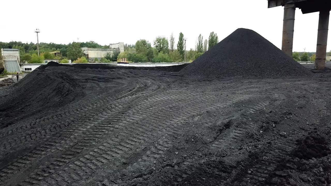 Warehouse of coal inventory plant. Yellow tractor loading the coal on the warehouse