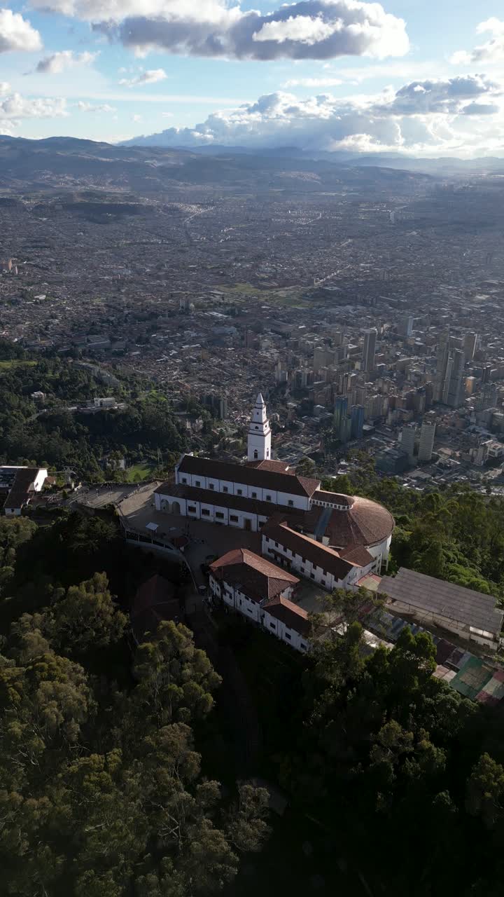 Vertical drone shot of Monserrate Sanctuary overlooking the massive, sprawling city of Bogota, Colombia