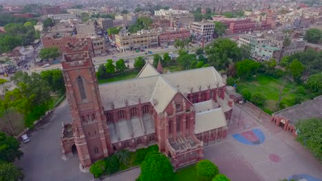 aerial view of a beautiful old church in the city, traffic is moving on the other side road of the church, beautiful greenery around the church, a flag on the top of the church