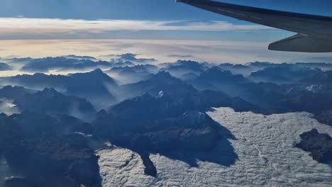 foggy snow covered alps from plane, visible wing