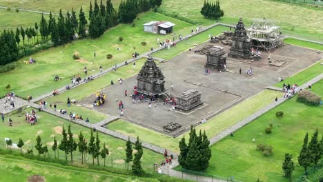 people enjoying ancient stone temple in indonesia, aerial orbit view