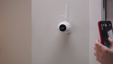 person interacting with a smart home security camera using a smartphone