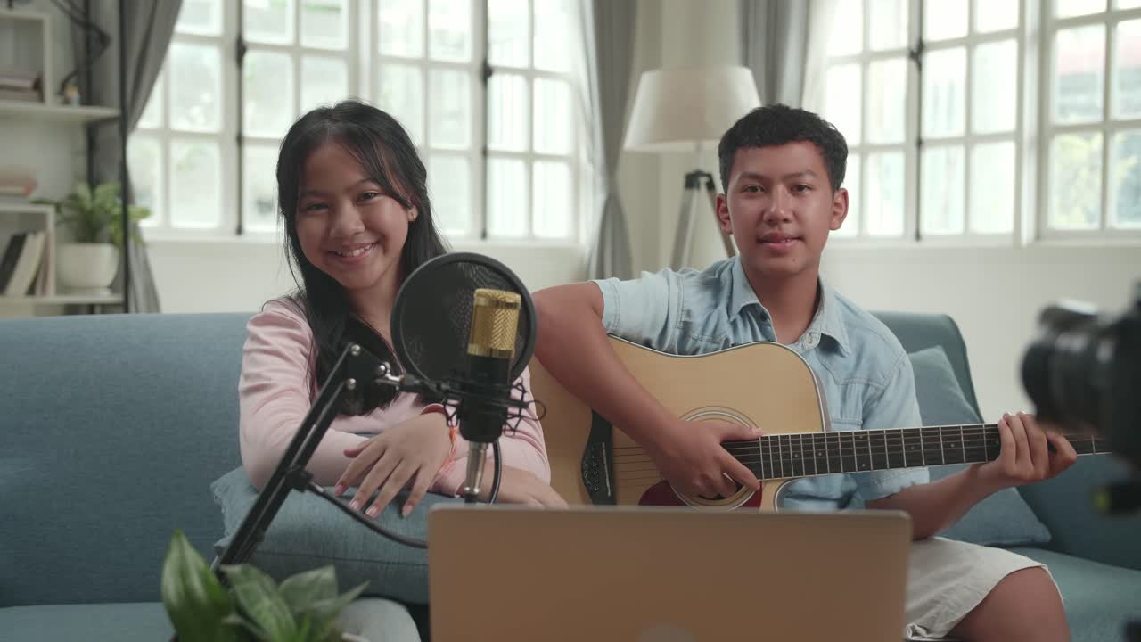 Two siblings playing acoustic guitar together
