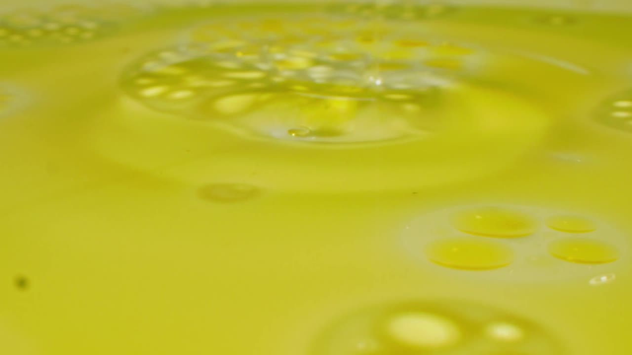 Liquido che si versa e si espande su una superficie oleosa gialla
