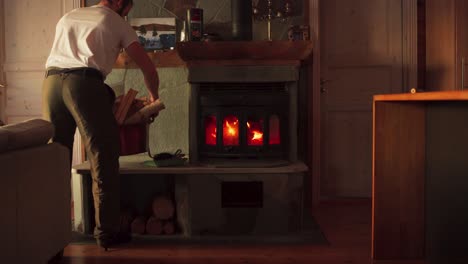 man coming in with a bucket of chopped firewood for wood burning stove at home