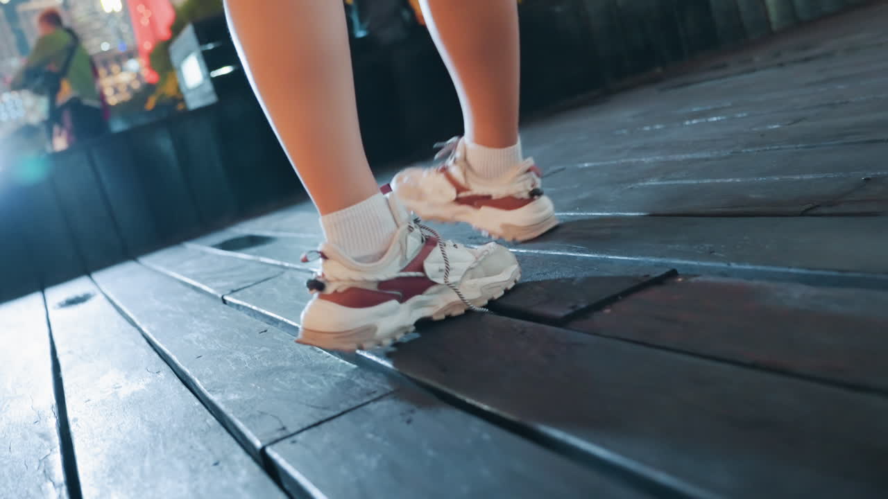 Energetic rooftop dance with sneakers, crop top and earbuds, dynamic arm gestures and quick footwork on wooden deck against dusky sky confident movement and rhythm as influencerstyle performer records