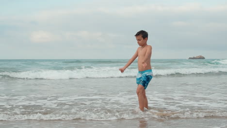 happy boy spending summer vacation at seaside. guy doing exercises at coastline.