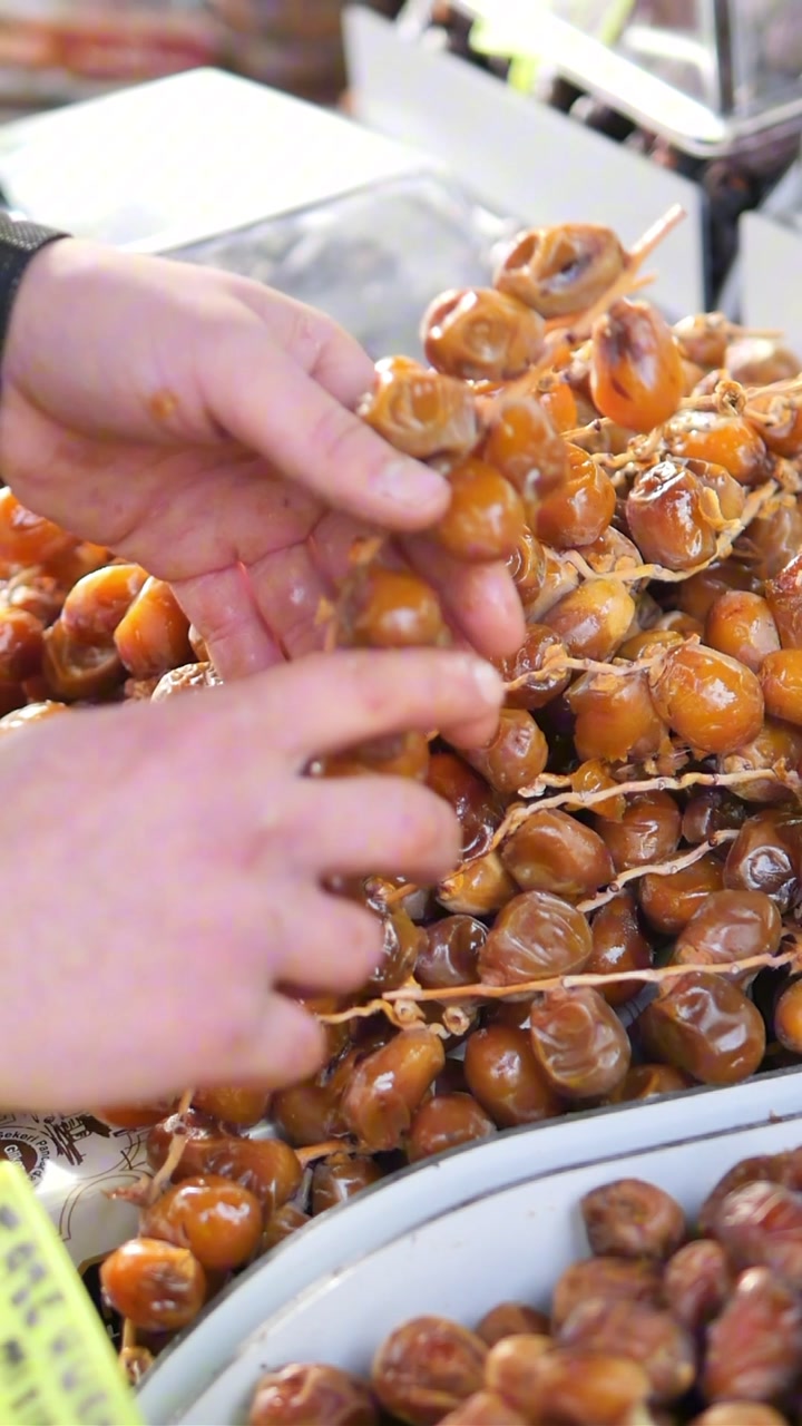 A Hand Selecting Fresh Dates from a Market Stall