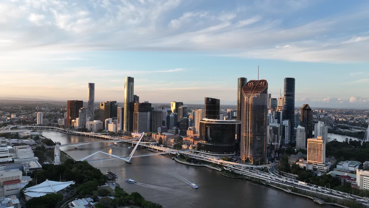 Langsom dronedrift ved den gyldne time over Brisbane-floden, med Queens Wharf og The Star Brisbane-tårnene, CityCat-færger under og CBD-skyline, Brisbane, QLD, Australien