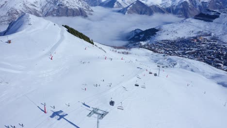 drone capturing lot of skiers skiing a snowy high mountain at day time
