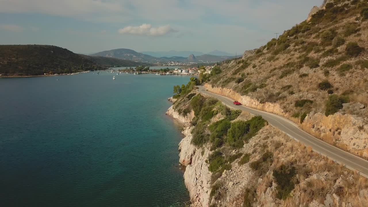 volando sobre el mar junto a un automóvil que recorre la costa en grecia