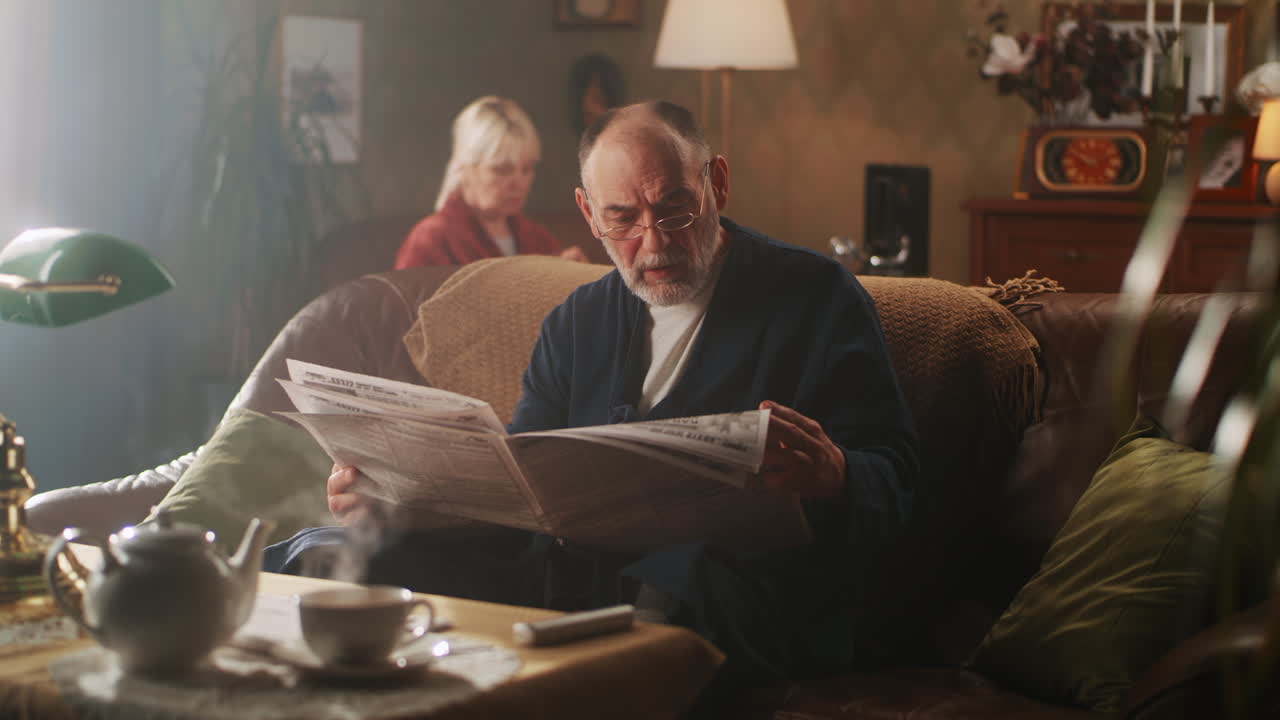 Elderly man reading newspaper in a cozy living room