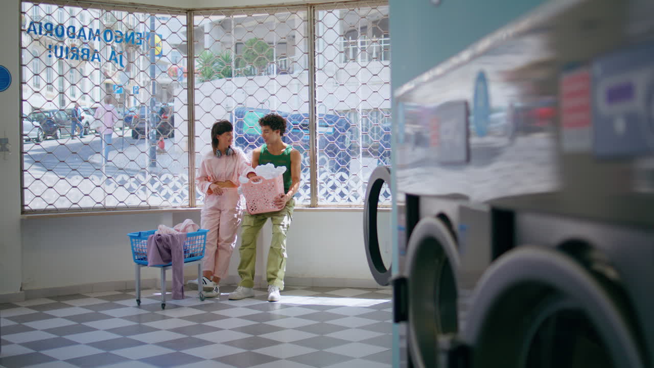 사랑하는 커플이 세탁실에서 대화하고 있습니다. 십대 소녀 남자가 공공장소에서 옷을 고 있습니다.