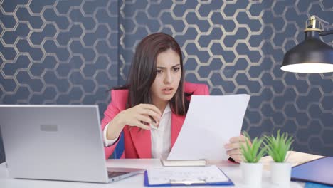 una joven mujer de negocios examina el papeleo y se enoja.