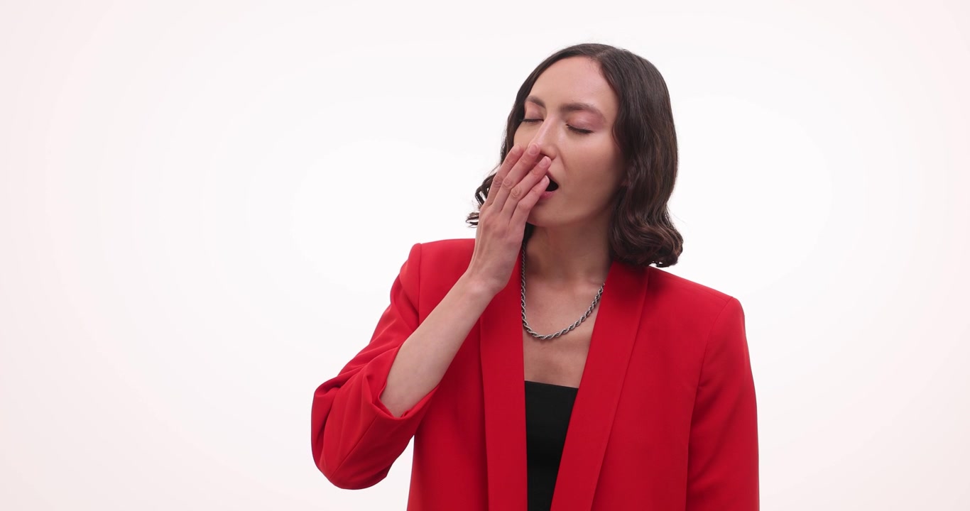 Tired woman yawns with hand covering mouth and rubs eyes