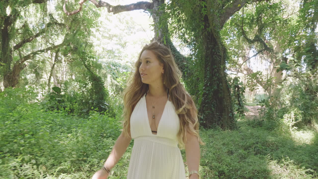 숲의 요정, 하얀 드레스를 입은 웃는 금발 소녀가 울창한 정글을 걷는다