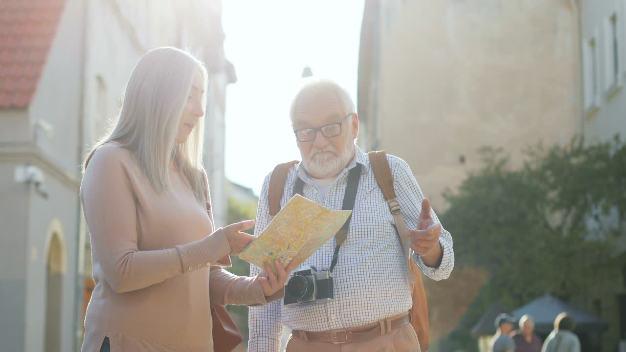 지도를 손에 들고 햇빛 속에 서서 길을 찾는 관광객 두 명
