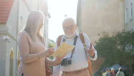 un par de turistas parados a la luz del sol con un mapa en las manos y buscando la ruta