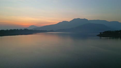 Hermosa-Puesta-De-Sol-Dorada-Sobre-El-Mar-Detrás-De-Las-Montañas-Y-Reflejo-De-La-Luz-En-El-Agua-En-Bhandardara,-Un-Complejo-Vacacional-Cerca-De-Igatpuri,-En-Los-Ghats-Occidentales