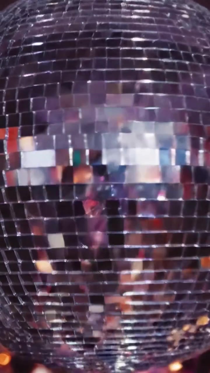 Una scintillante palla da discoteca illumina una vivace pista da ballo, creando un'atmosfera magica piena di luci colorate e festaioli gioiosi a una celebrazione notturna.