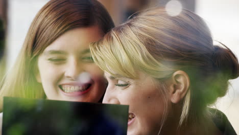 two women using digital tablet drinking coffee in cafe