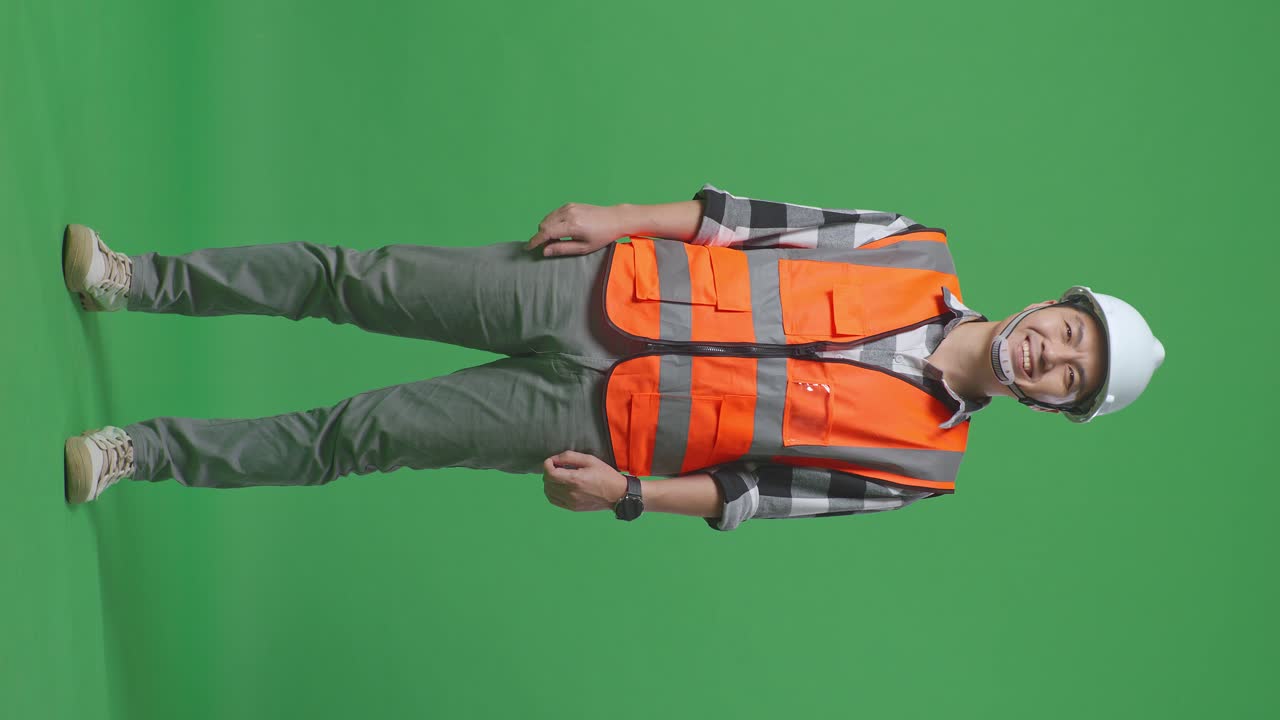 Full Body Of Asian Male Engineer With Safety Helmet Smiling To Camera While Standing In The Green Screen Background Studio