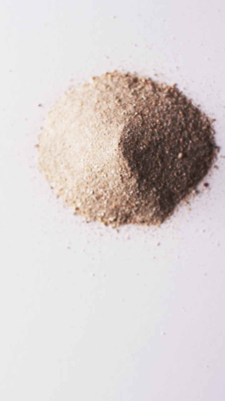 Vertical video of close up of heap of sand grains and copy space on white background