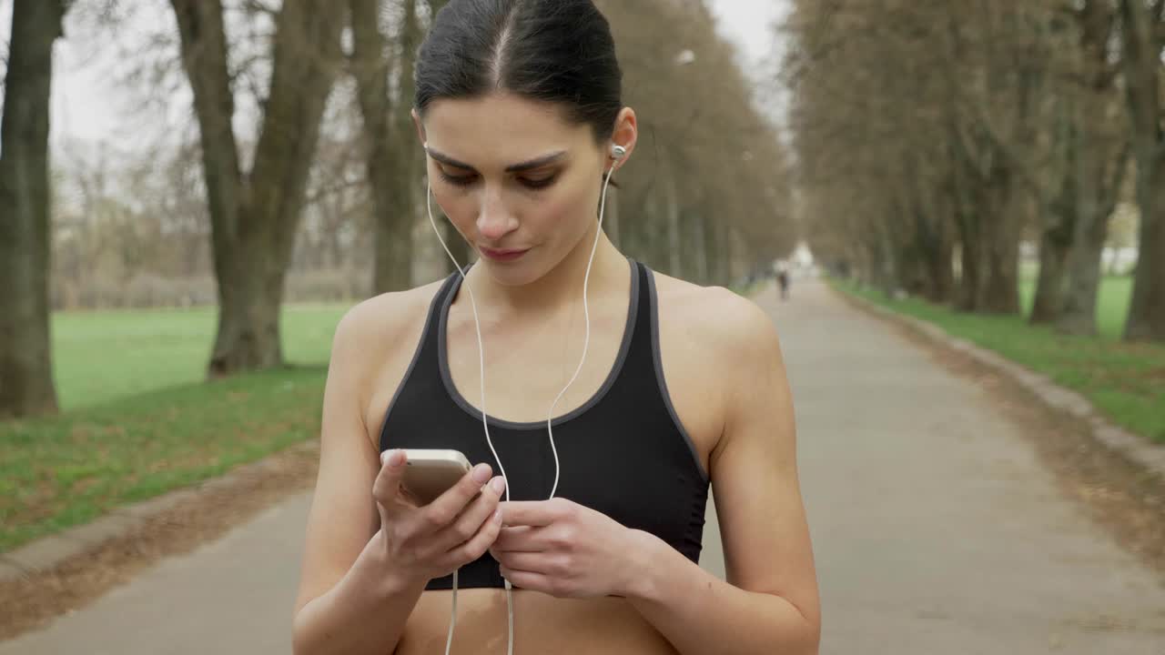 Young fsport girl is turning on music on her smartphone, running, healthy lifestyle, sport conception