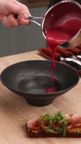 chef pouring beetroot sauce into a bowl