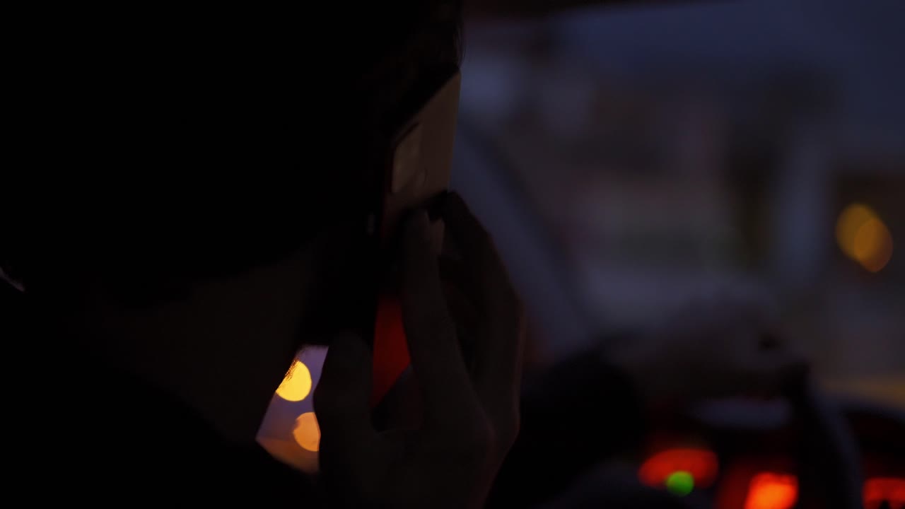 밤 도시 에서 운전 하는 동안 전화 로 이야기 하는 사람