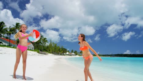 caucasian sisters in swimwear playing with beach ball