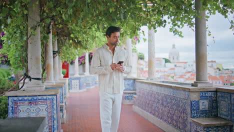 relaxed macho walking viewpoint alley. handsome  man taking smartphone