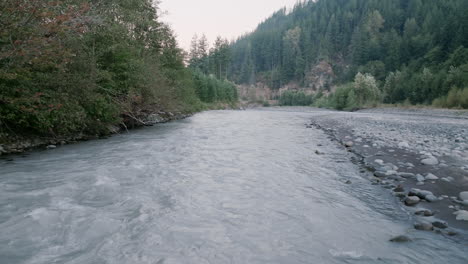 aerial footage following water that is flowing down a riverbed in the cascade mountains