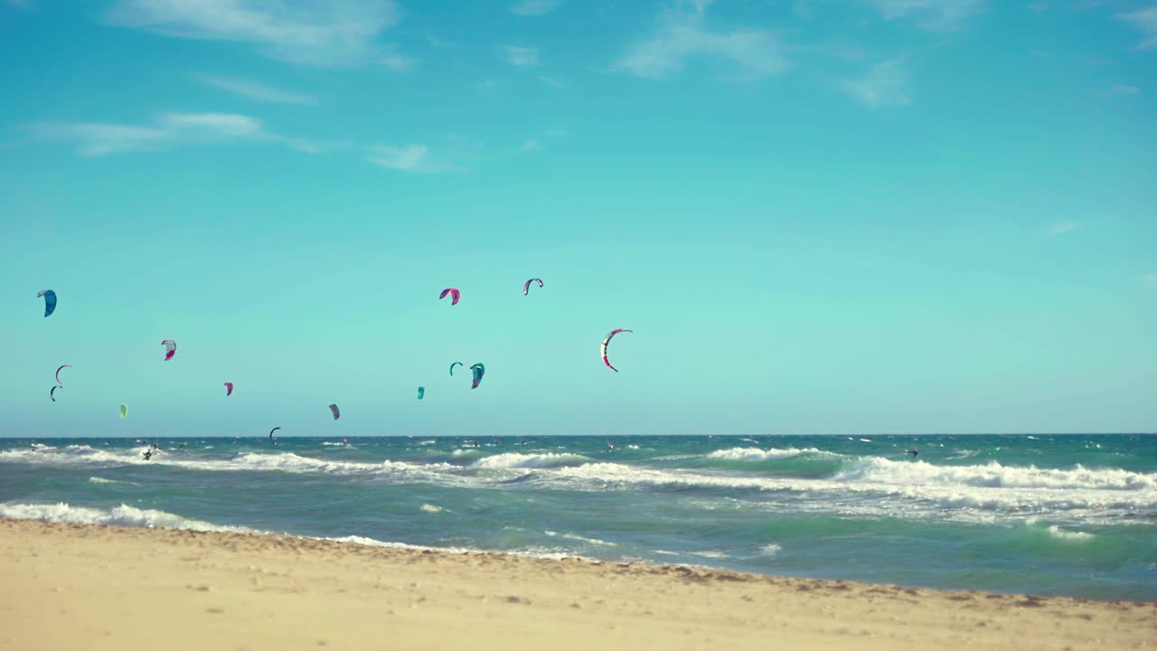 día ventoso en la playa con varios kitesurfistas en el fondo