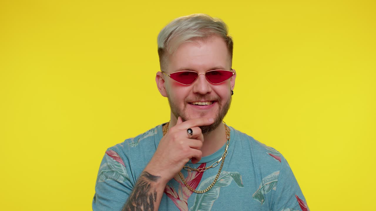 un hombre feliz y juguetón quitándose las gafas de sol, parpadeando los ojos, mirando a la cámara con una sonrisa, guiñando el ojo, coqueteando.