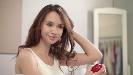 brunette woman applying hair spray in bathroom