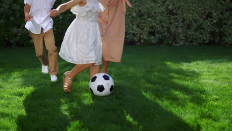 parents and children feet playing football. father throwing soccer ball in air