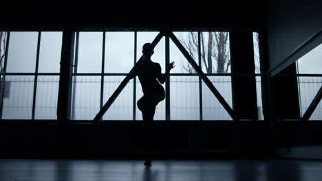 dancer silhouette grinding dance steps indoors. athletic girl dancing in studio.