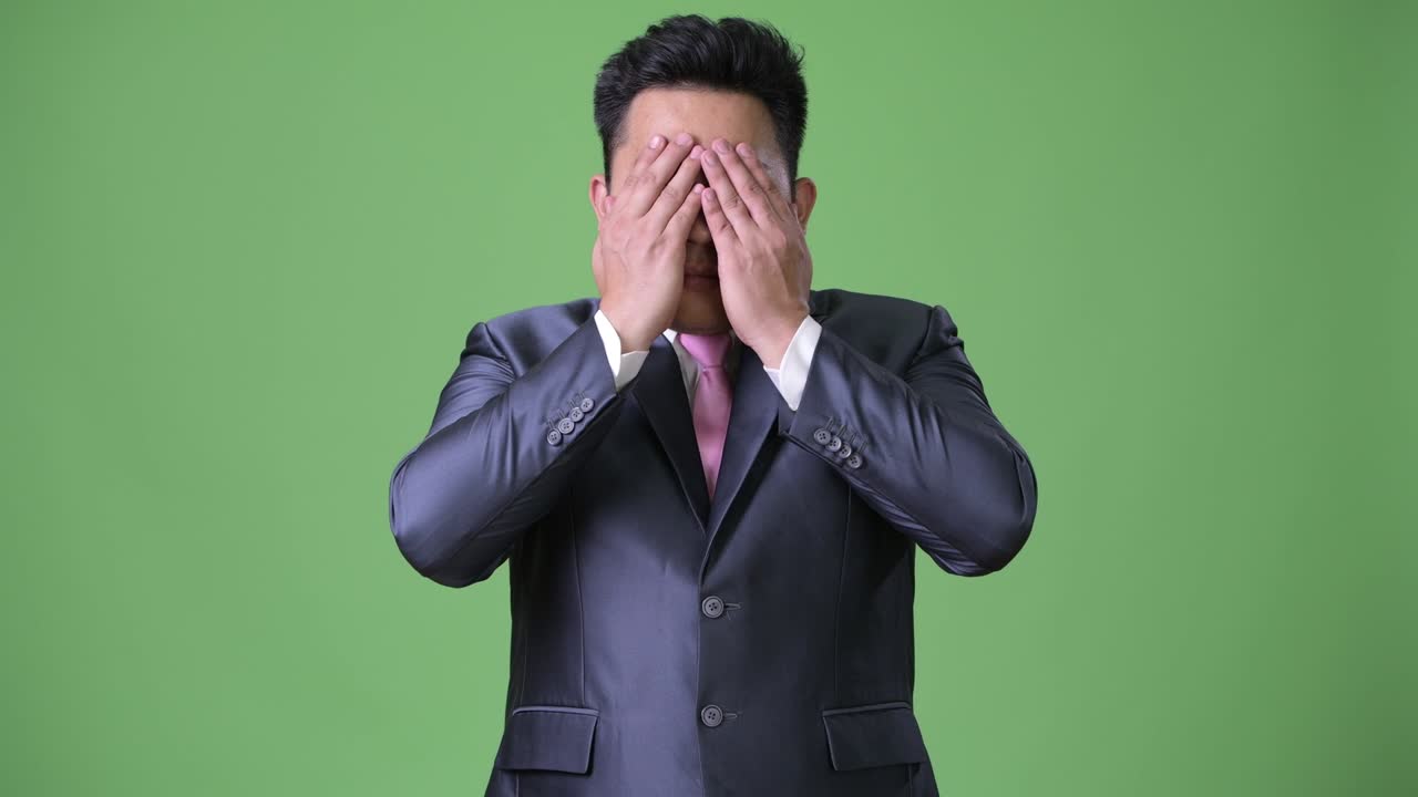 초록색 배경에 젊은 잘생긴 과체중 아시아 사업가