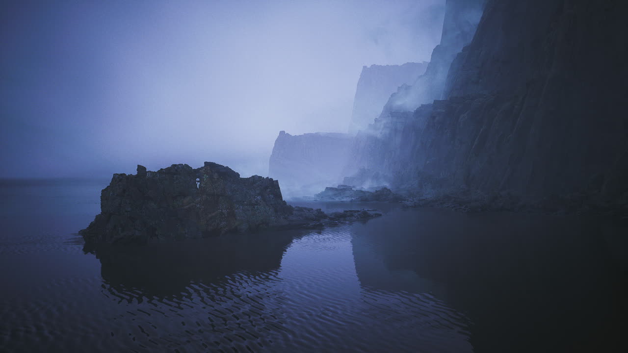Mysterious fog envelops rocky coastline at dawn near calm waters